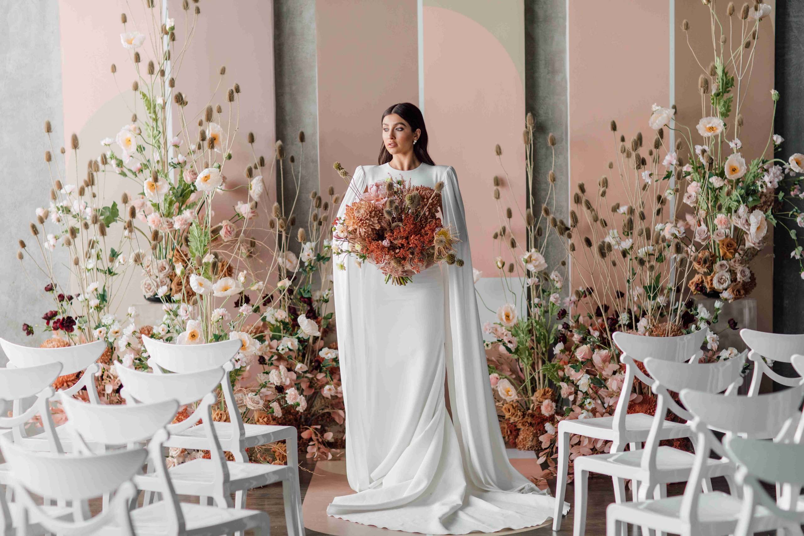 Bride holding a bouquet among tall blush and rust floral installations