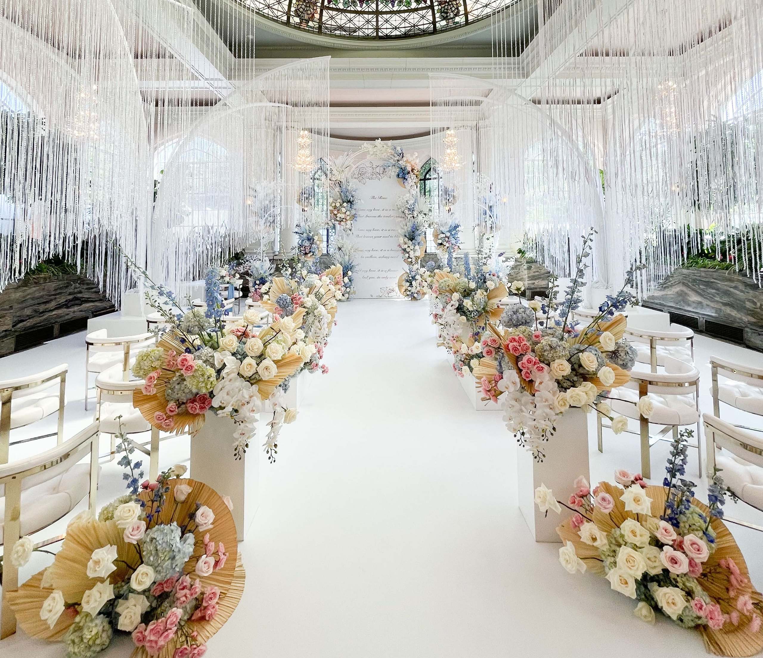 Ceremony aisle under crystal strands with pastel floral pedestals