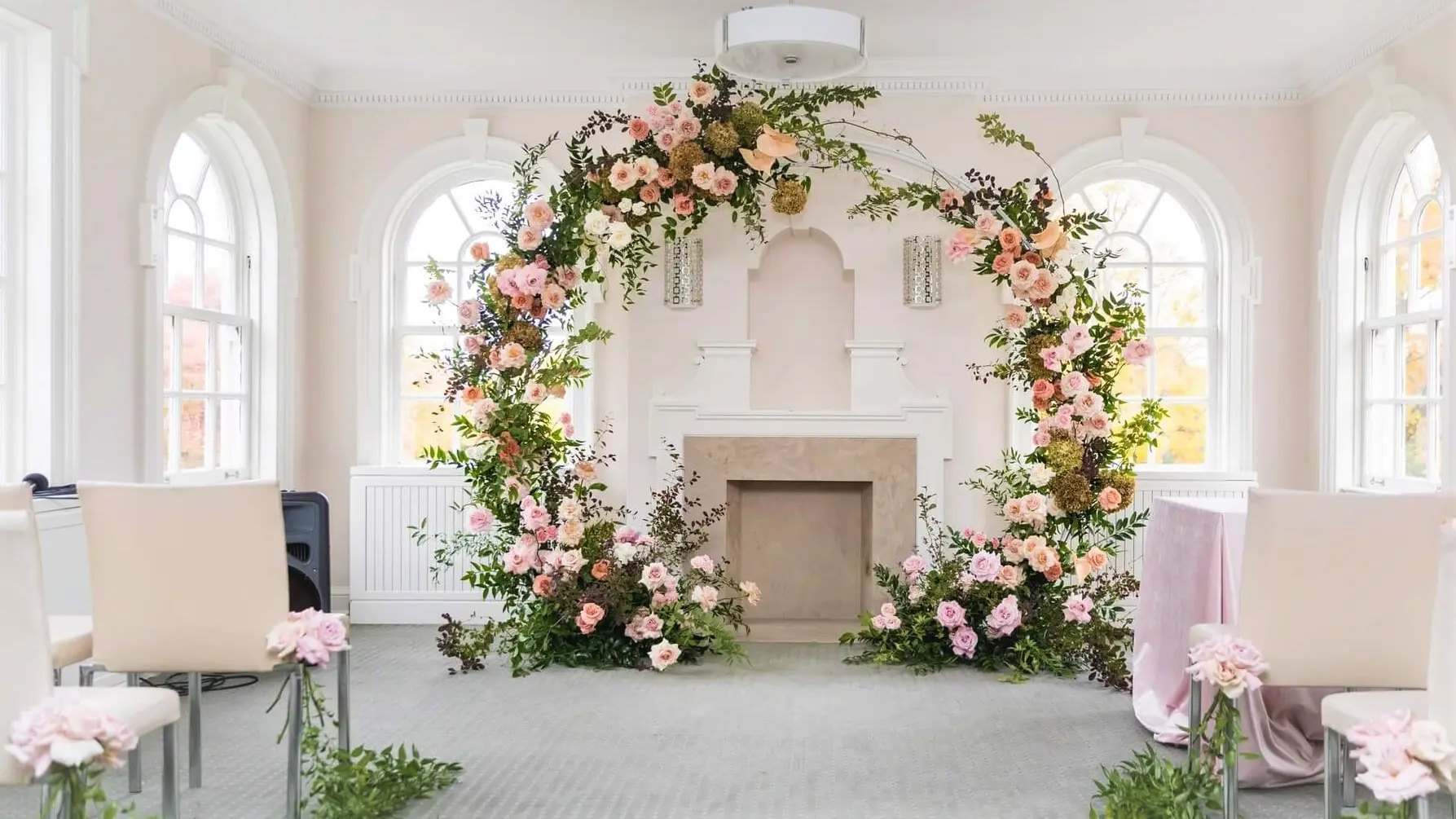Blush and peach floral arch framing a white fireplace