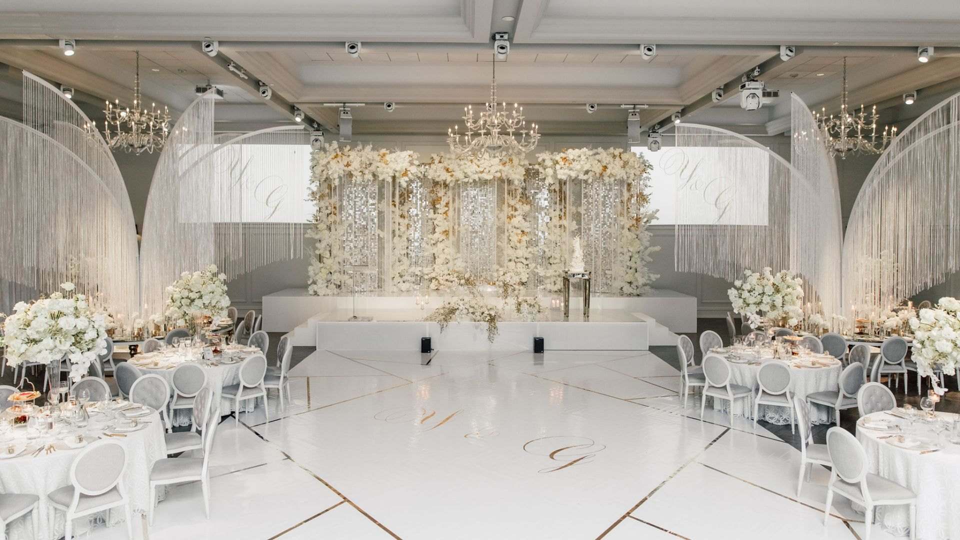 White gala room with a cream floral stage wall and crystal curtains