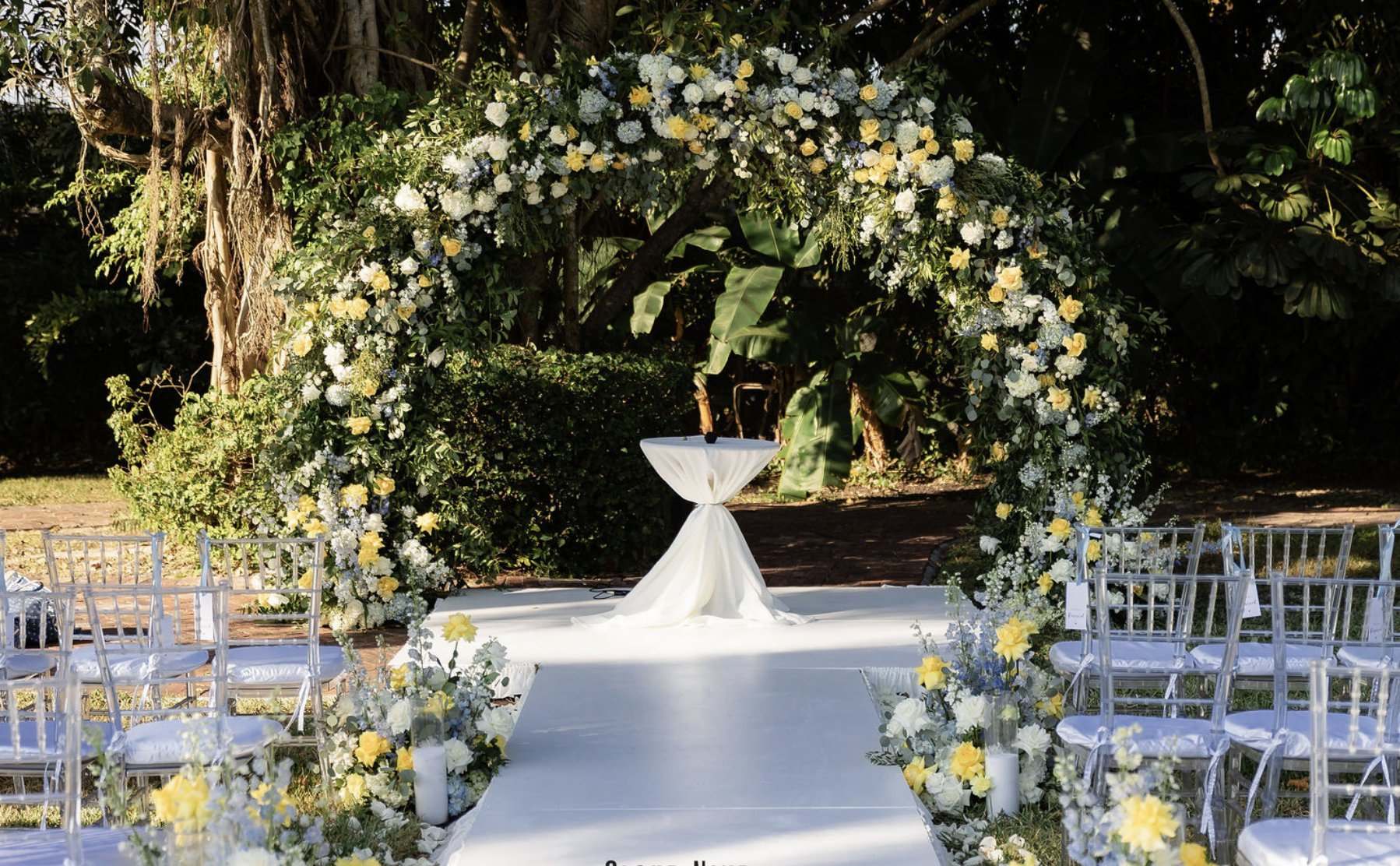 Circular white and yellow floral arch under oak trees