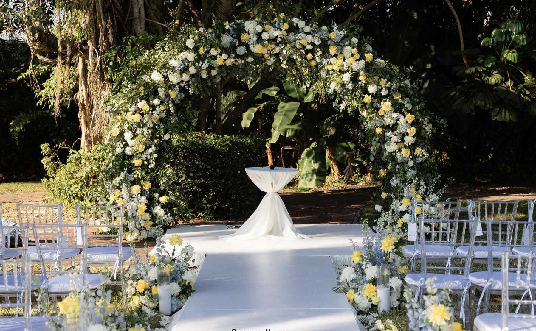 Circular white and yellow floral arch under oak trees