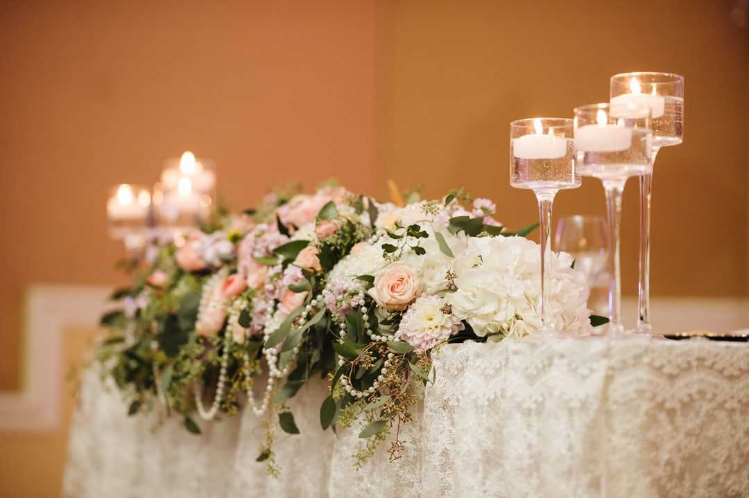 Head table garland of blush roses and greenery with tall candles