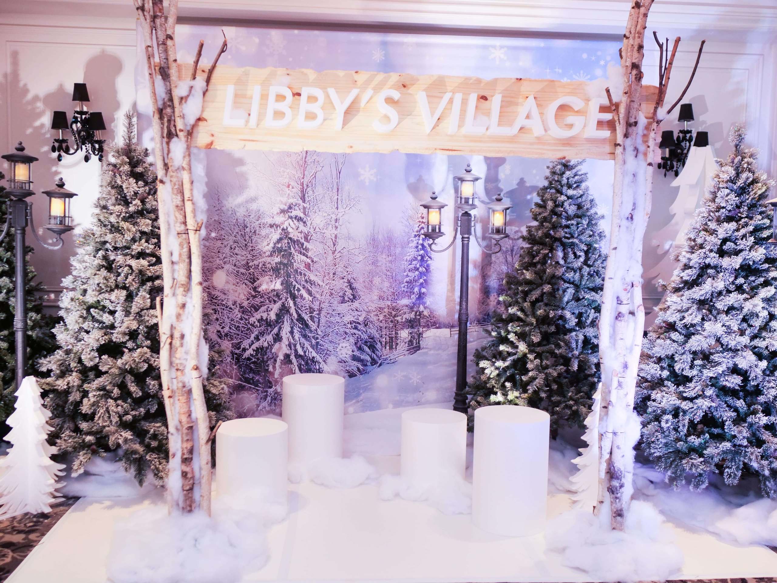 Winter village set with birch trees, snow-covered pines and a hanging sign
