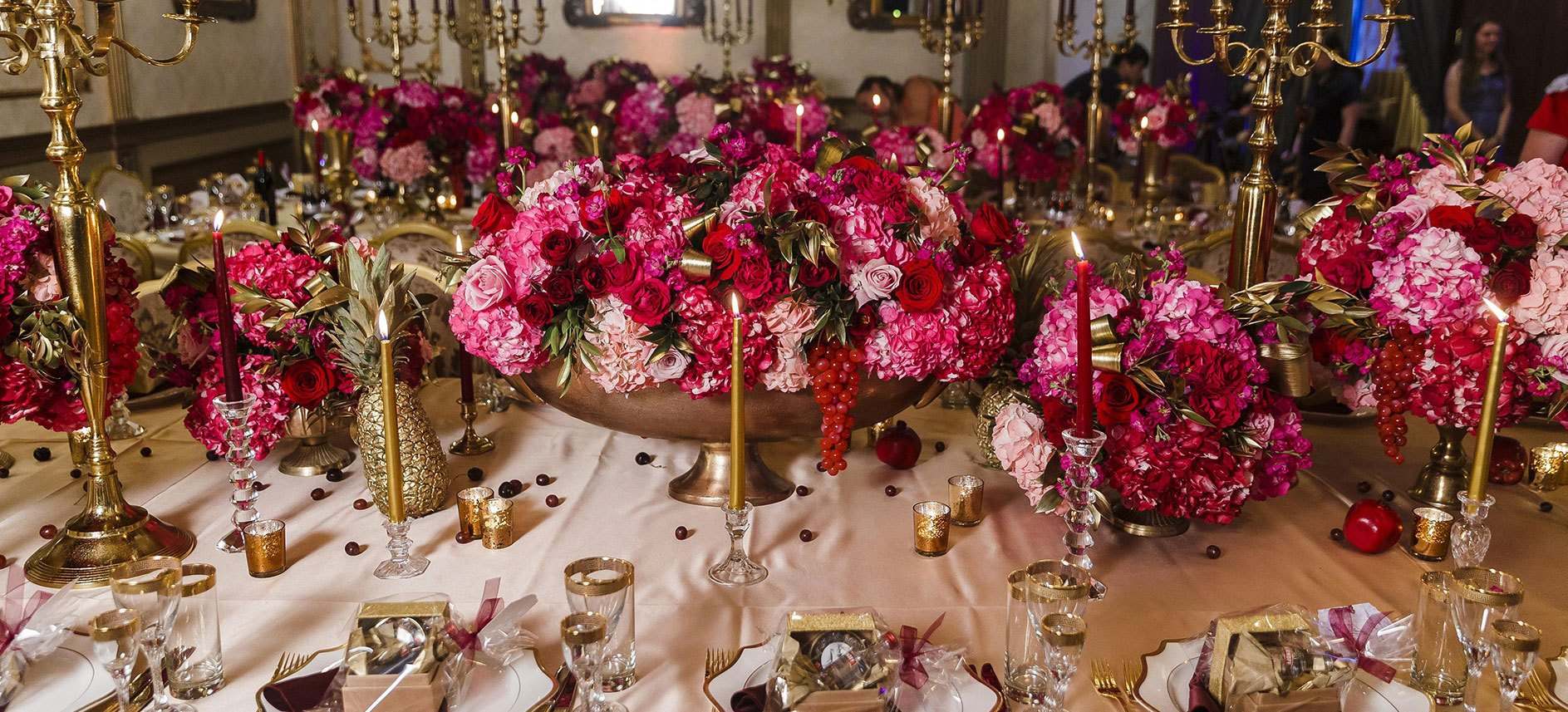 Dense magenta and crimson rose tablescape with gold candlesticks
