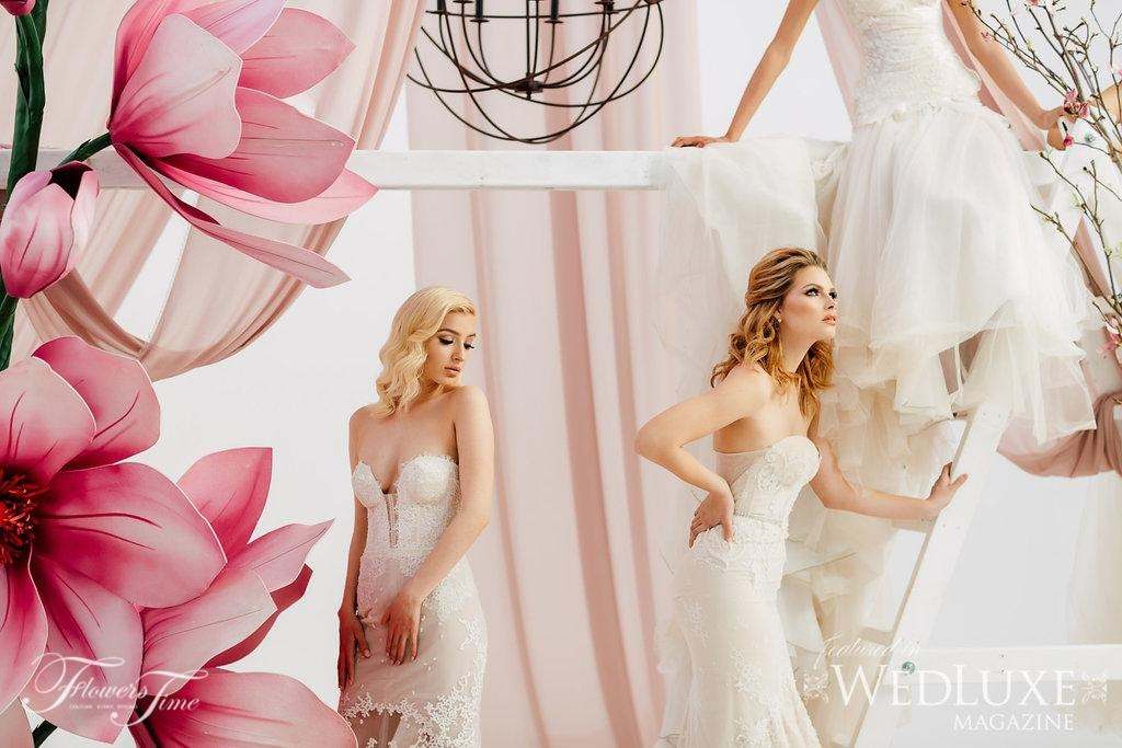 Brides posing beside oversized pink magnolia sculptures