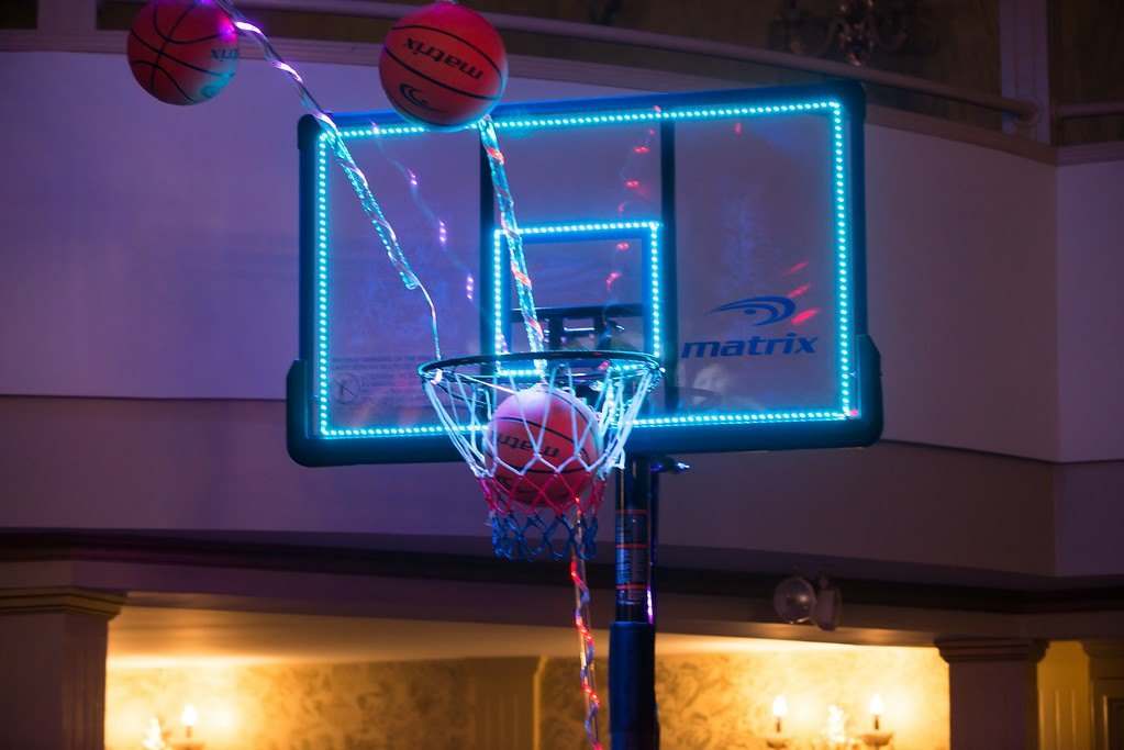 Neon basketball hoop at a party with red balloons
