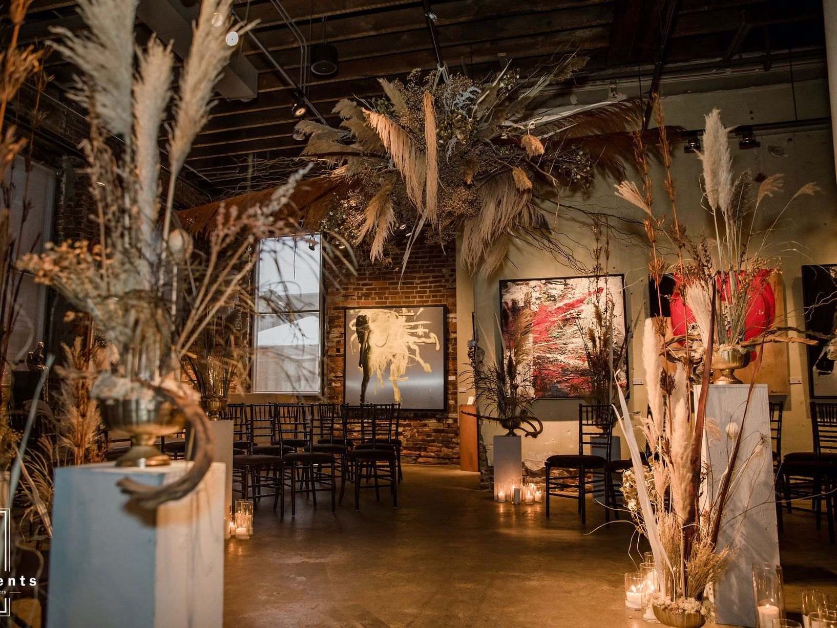 Gallery dinner under towering pampas and dried arrangements in amber light