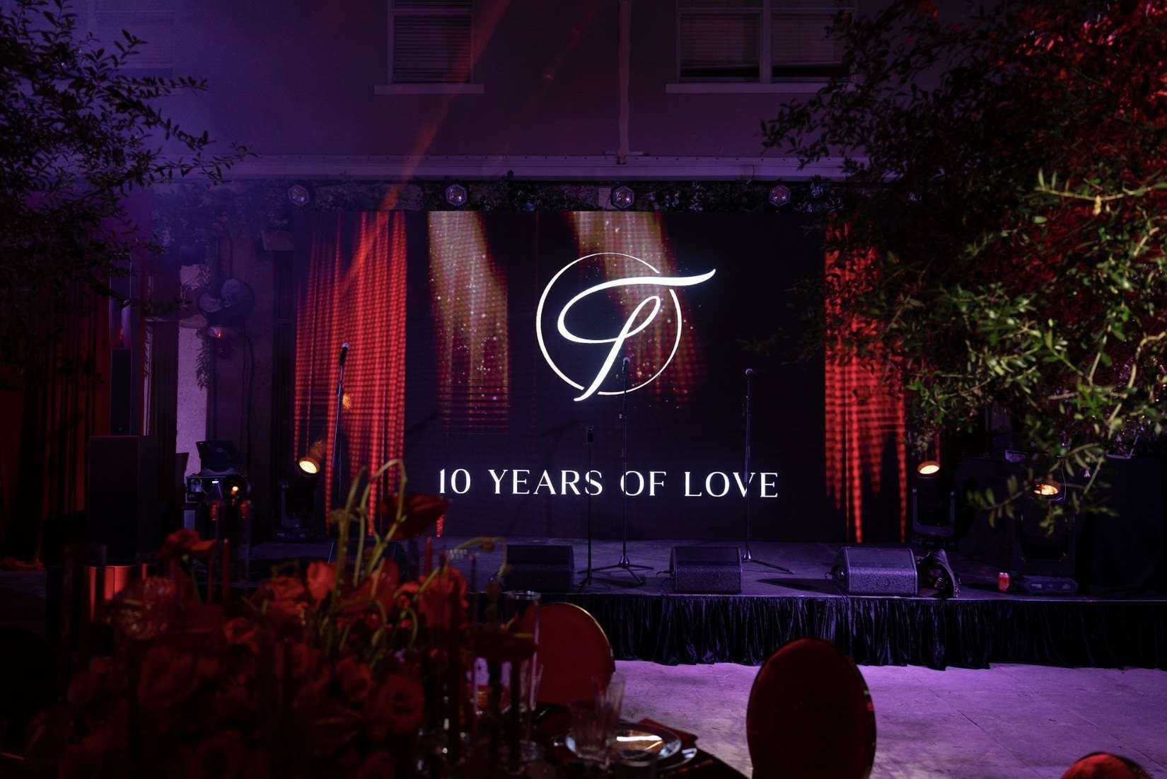 Anniversary stage with a monogram screen reading 10 Years of Love and red lighting