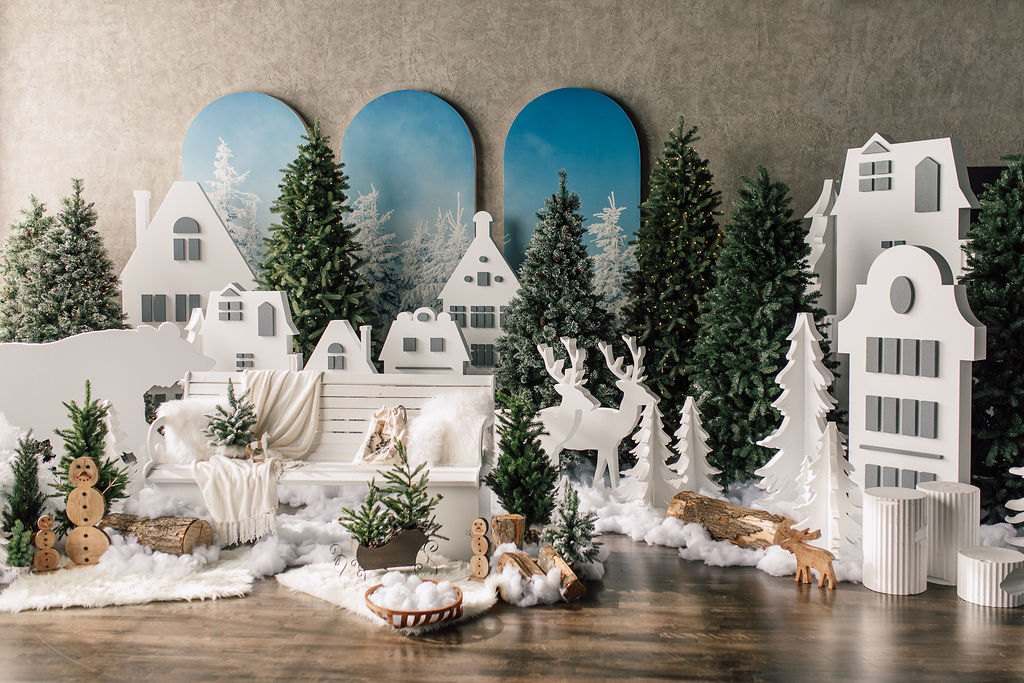 White paper houses, pines and deer figures under blue arched panels